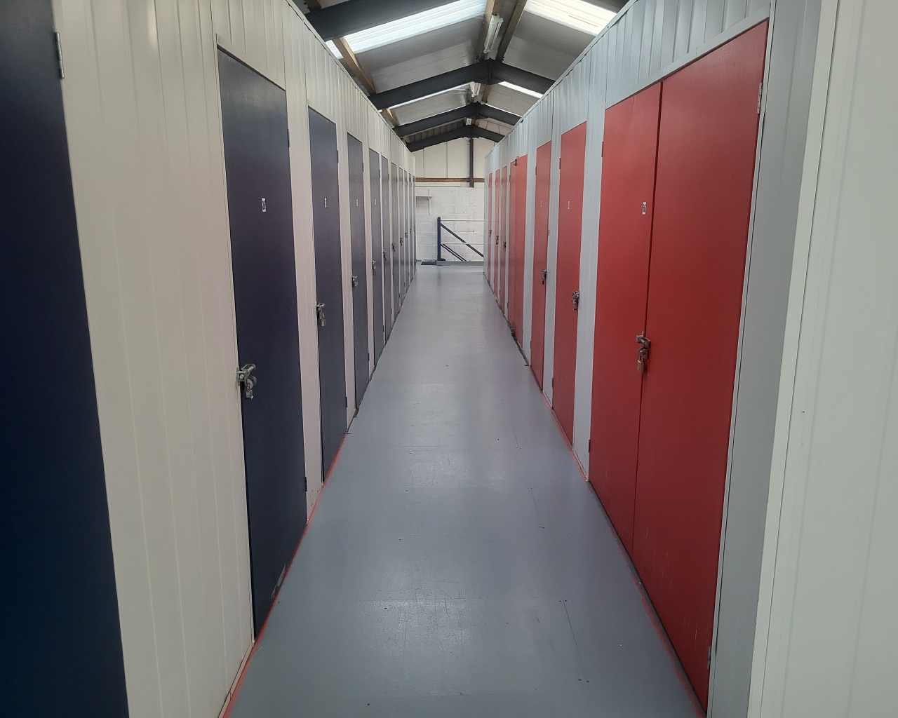 Photo of corridor with red/blue doors leading into storage containers.